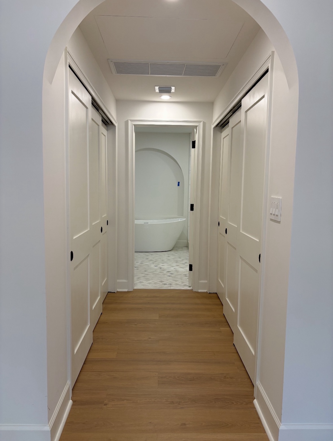White shaker doors in arched hallway